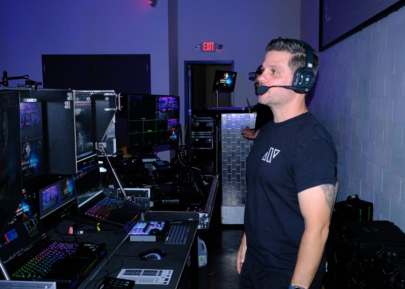 An AVP.Live operator in a headset at the production desk, switching a live mixed martial arts broadcast from the venue floor